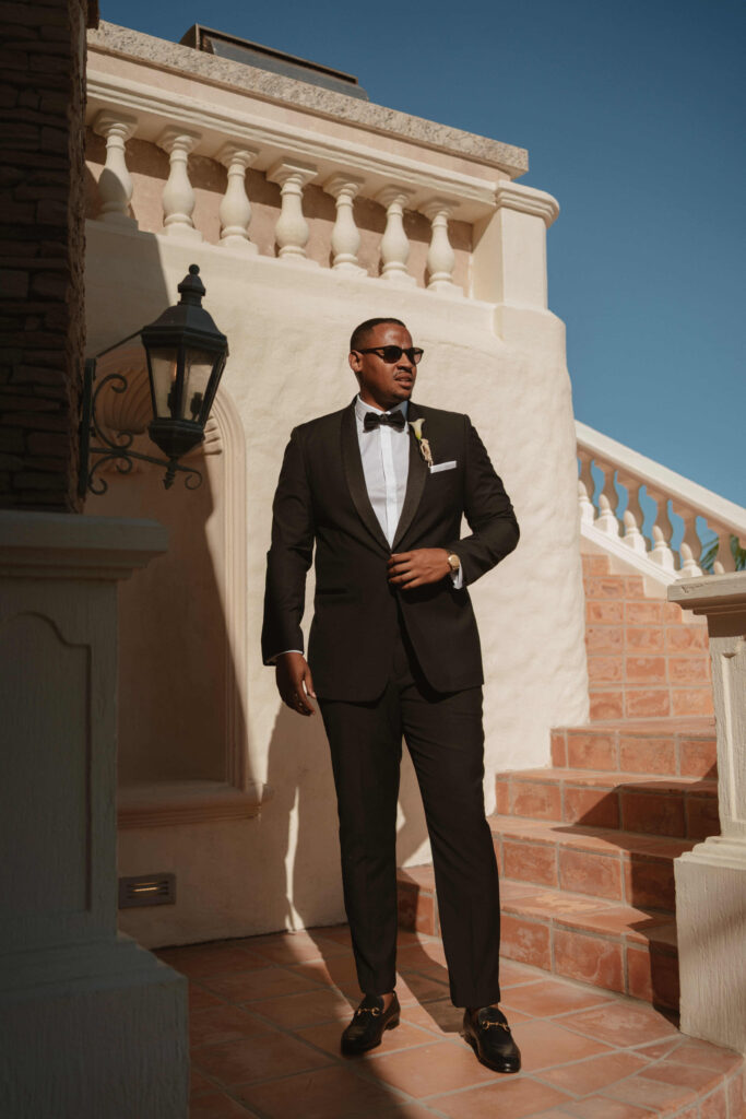 Groom in a black tuxedo on the steps of Casa Mariposa Villa