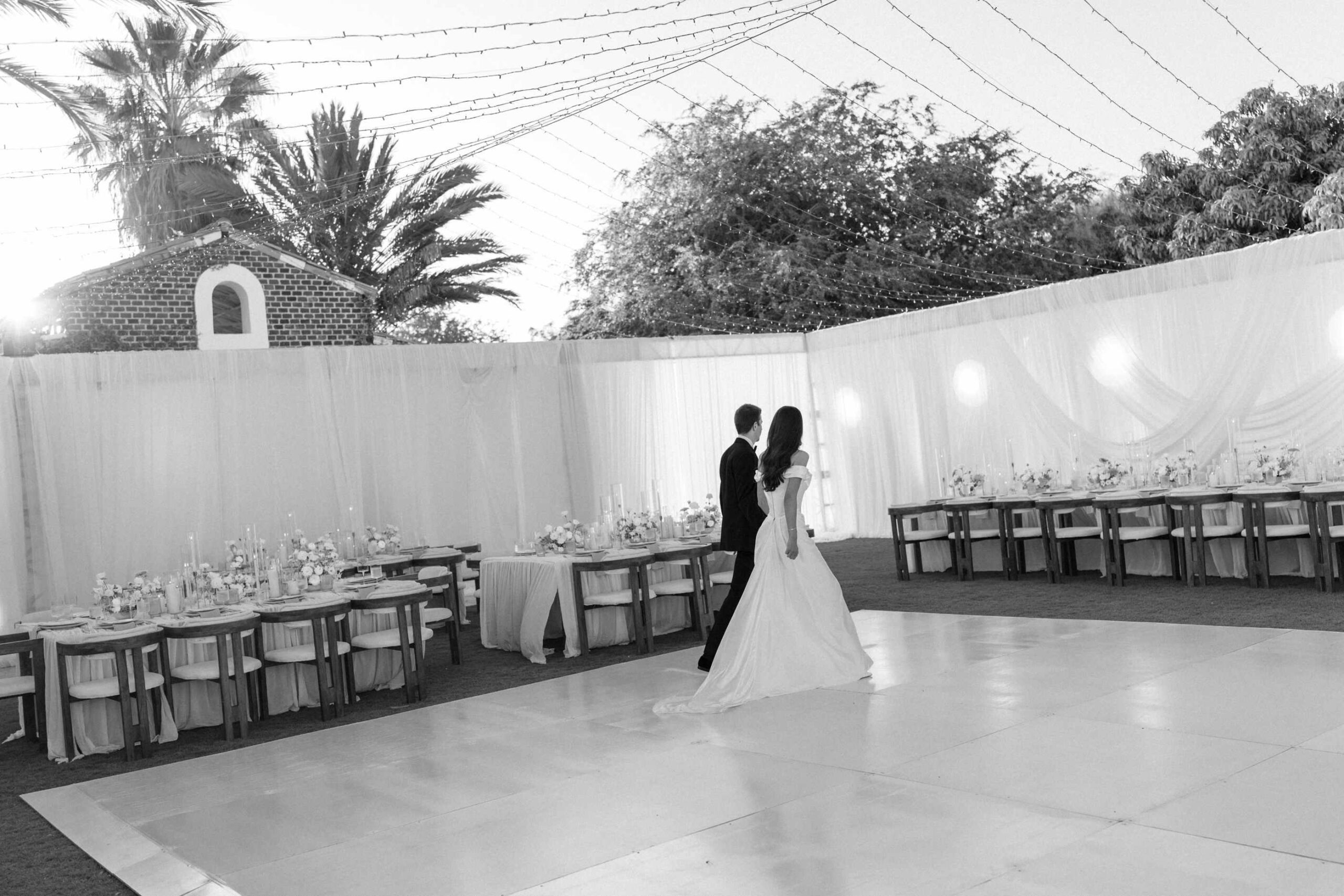 Long reception table with white florals and neutral linens inside a draped tent at Flora Farms